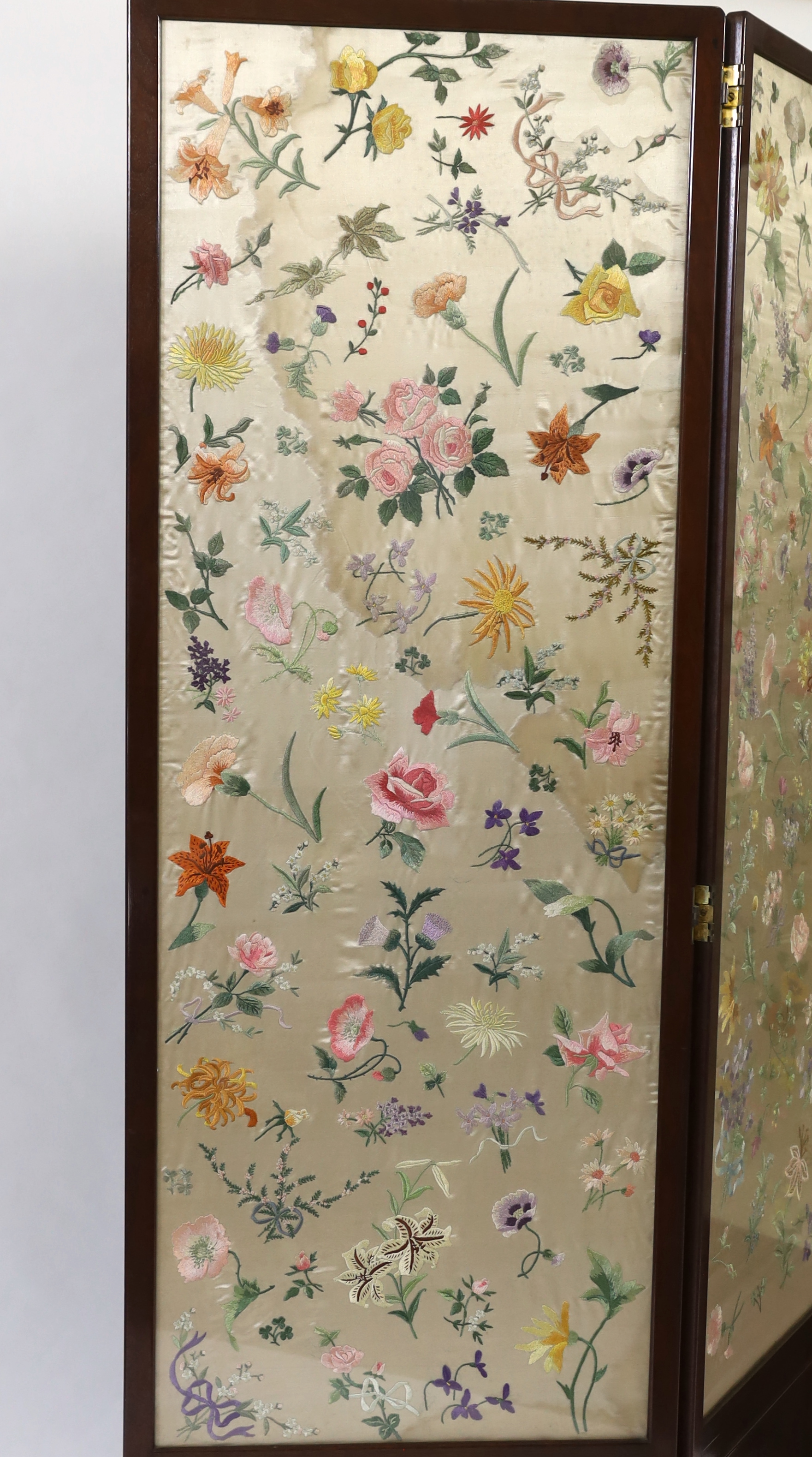 An Edwardian mahogany three fold screen with three panels of later (possibly 1920’s) hand embroidered, multi coloured, silk flowers, 50.5cm wide x 139cm high